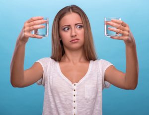 Portrait of a pretty girl holding two glasses with clean water i