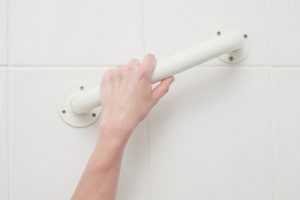 A female hand is grabbing an assistive handle in the bathroom